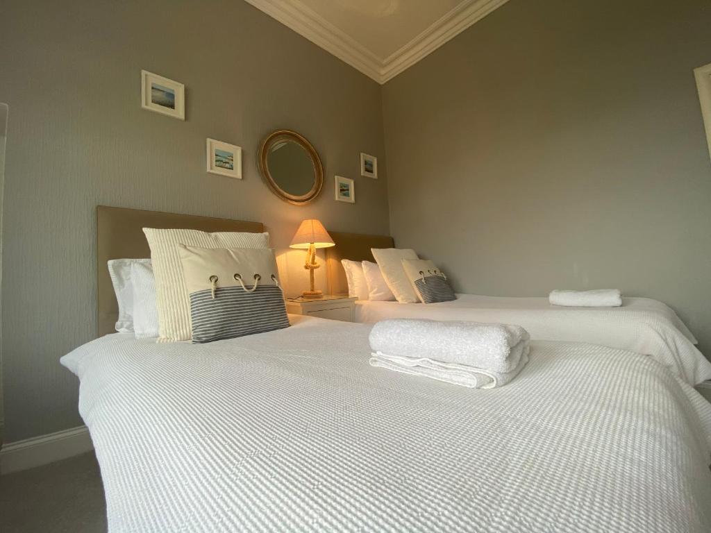 a bedroom with two beds with white sheets and a lamp at The Old Rectory in Largs