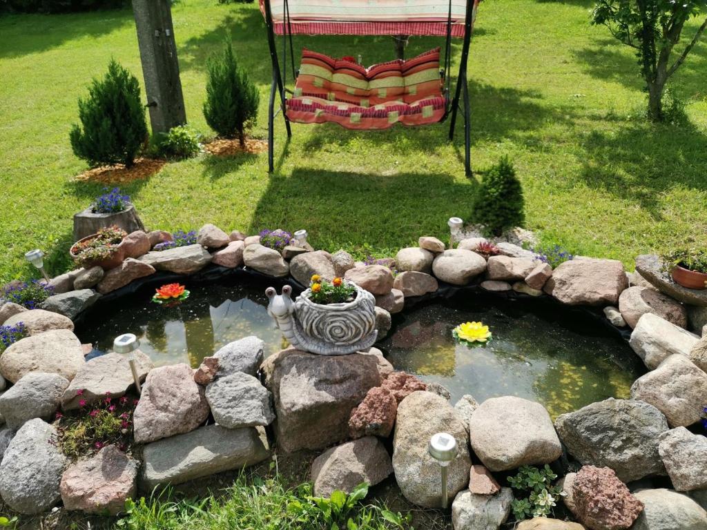 un jardín con un estanque y una silla en un patio en U Garnuszka, en Krasnopol