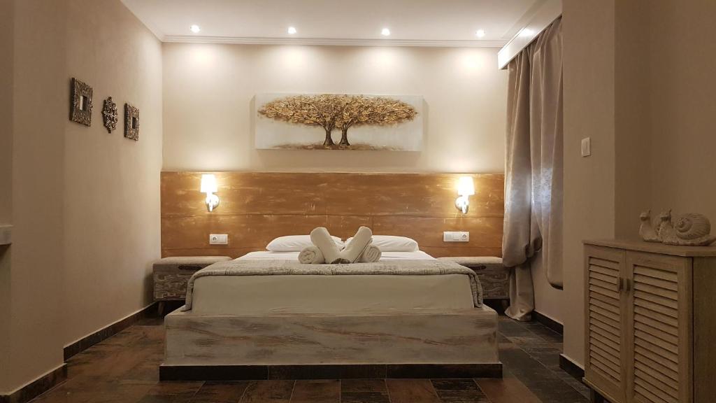 a bedroom with a bed with a tree on the wall at Agrili Apartments & Rooms in Elia