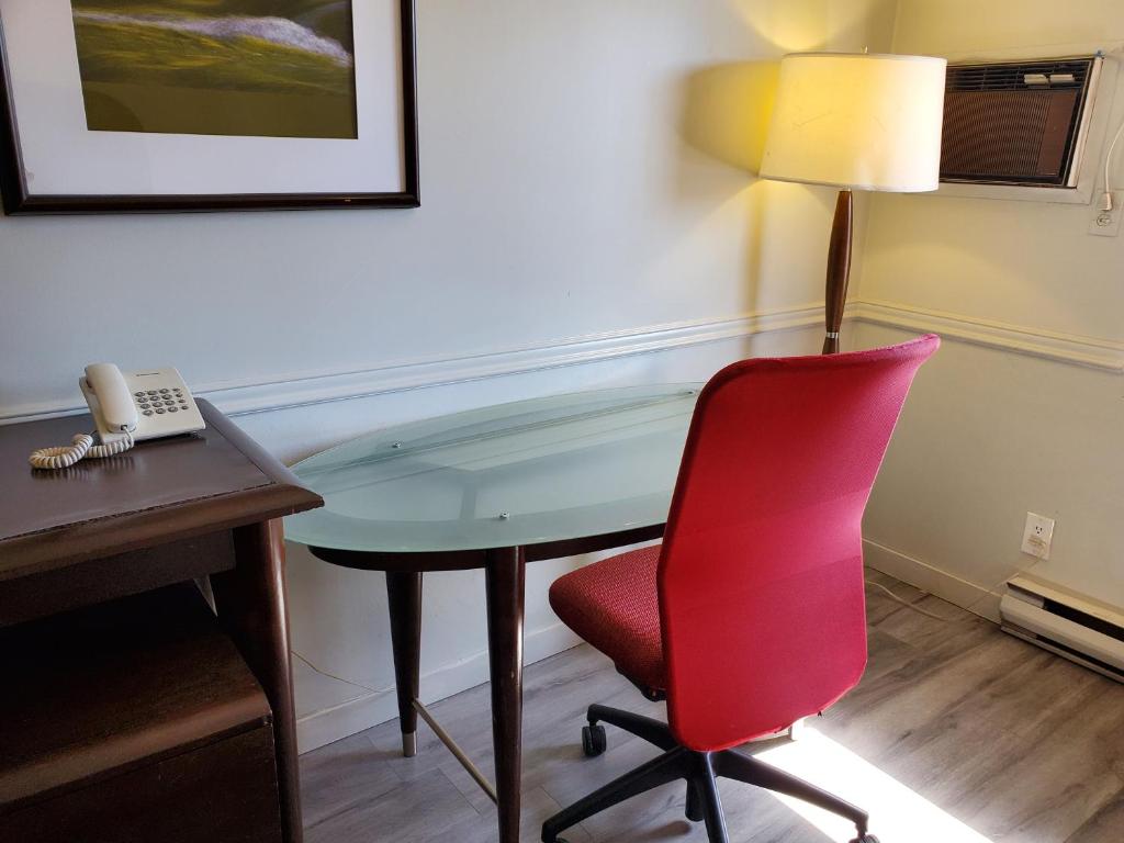 a desk in a room with a red chair and a phone at Alpine Inn Abbotsford in Abbotsford