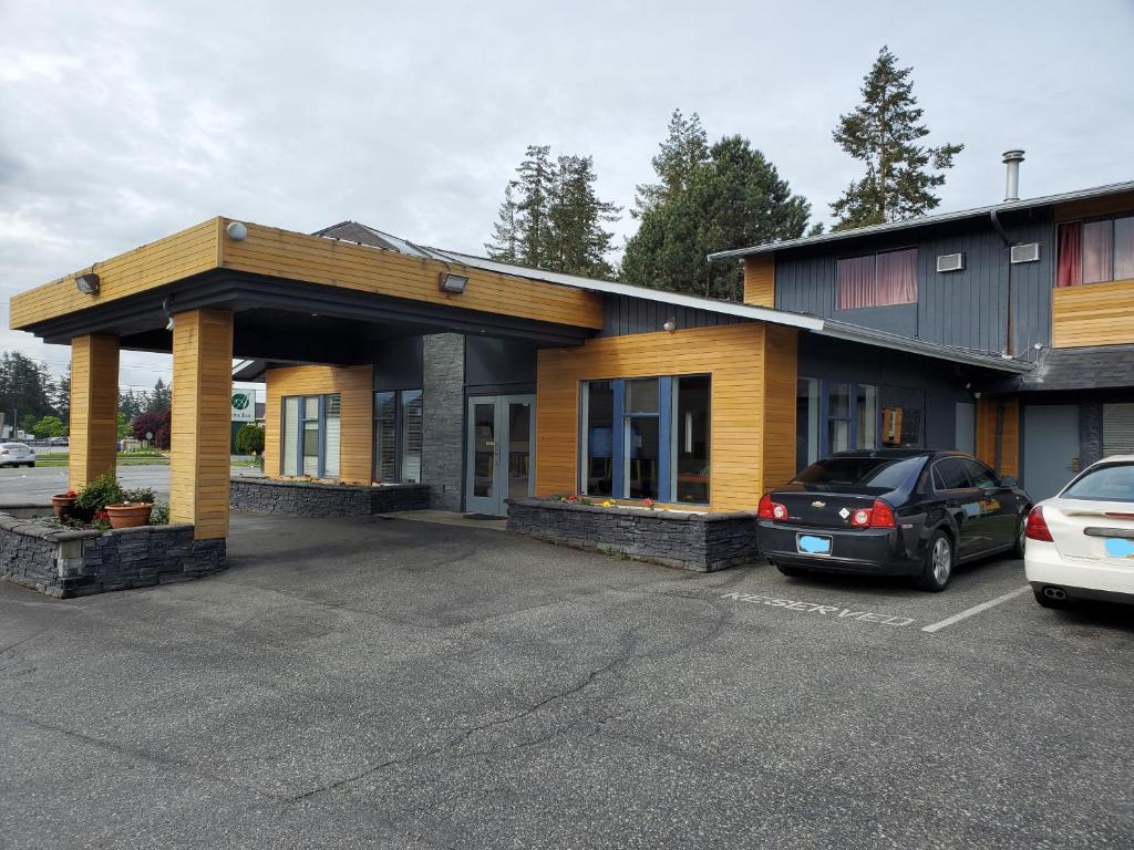 a building with a car parked in a parking lot at Alpine Inn Abbotsford in Abbotsford