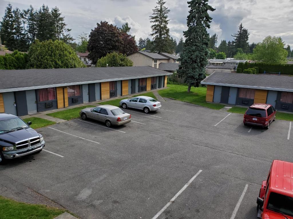 a parking lot with cars parked in front of a building at Alpine Inn Abbotsford in Abbotsford