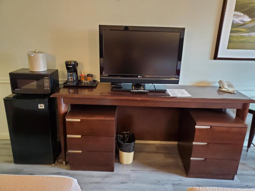 a computer desk with a television and a printer at Alpine Inn Abbotsford in Abbotsford