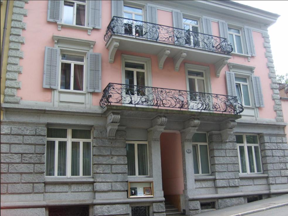 un edificio de color rosa con un balcón en el lateral. en Residence zur Musegg, en Lucerna