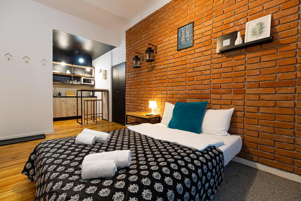 a bedroom with a large bed with a brick wall at Apartamenty Prosta - Podmurna in Toruń