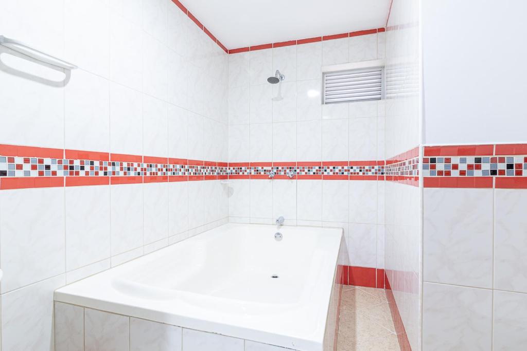 a bathroom with a white tub and red and white tiles at Hotel El Deportista in Medellín