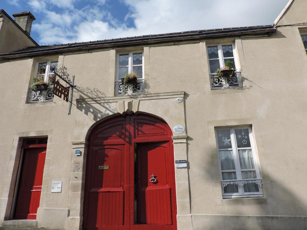 a building with a red door and two windows at La Closerie Teranga in Bayeux