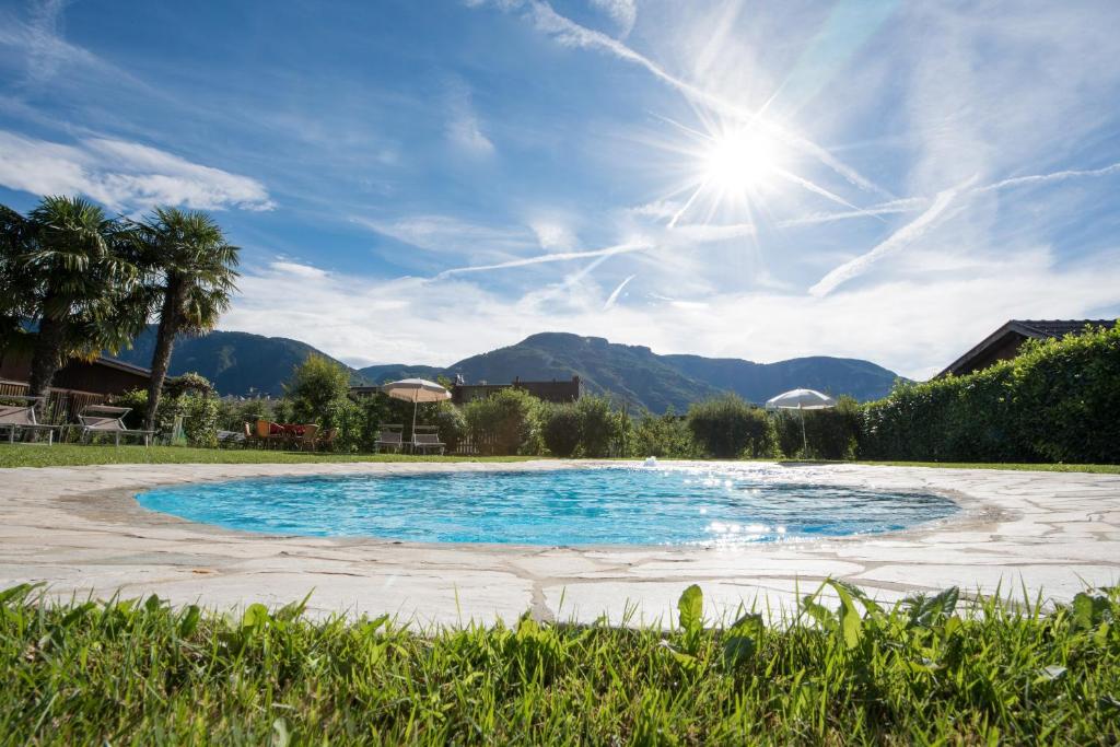 una piscina con el sol en el cielo y las montañas en Pension Sandhofer en Nalles