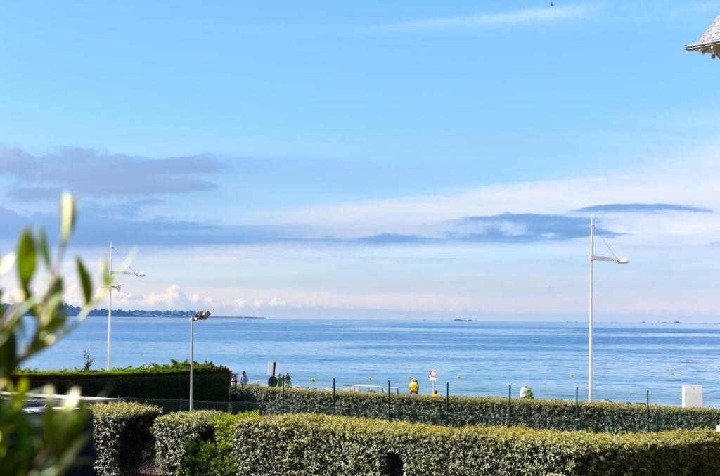 uma vista para o oceano com moinhos de vento e uma cerca em Villa neuve sur pilotis vue mer à 30m de la plage em Plérin