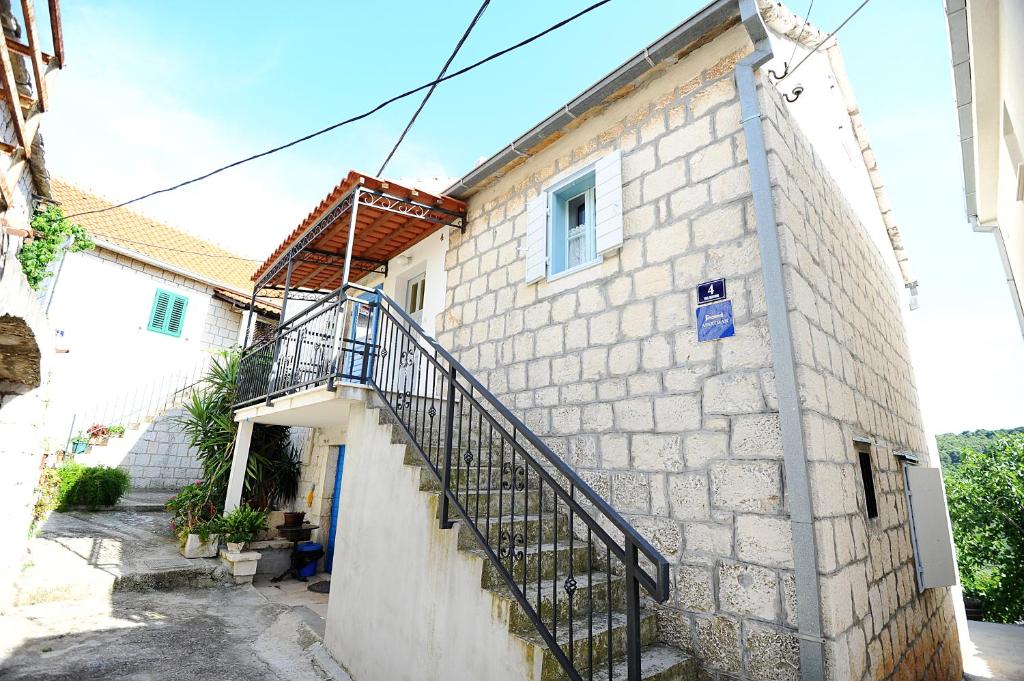 una casa in pietra con una scala sul lato di Apartments Rejo a Okrug Donji