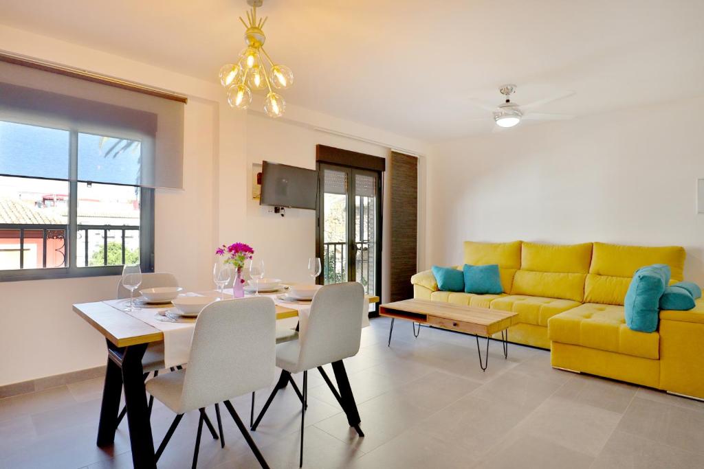 a living room with a dining table and a yellow couch at SunShine Vista al Compás in Córdoba