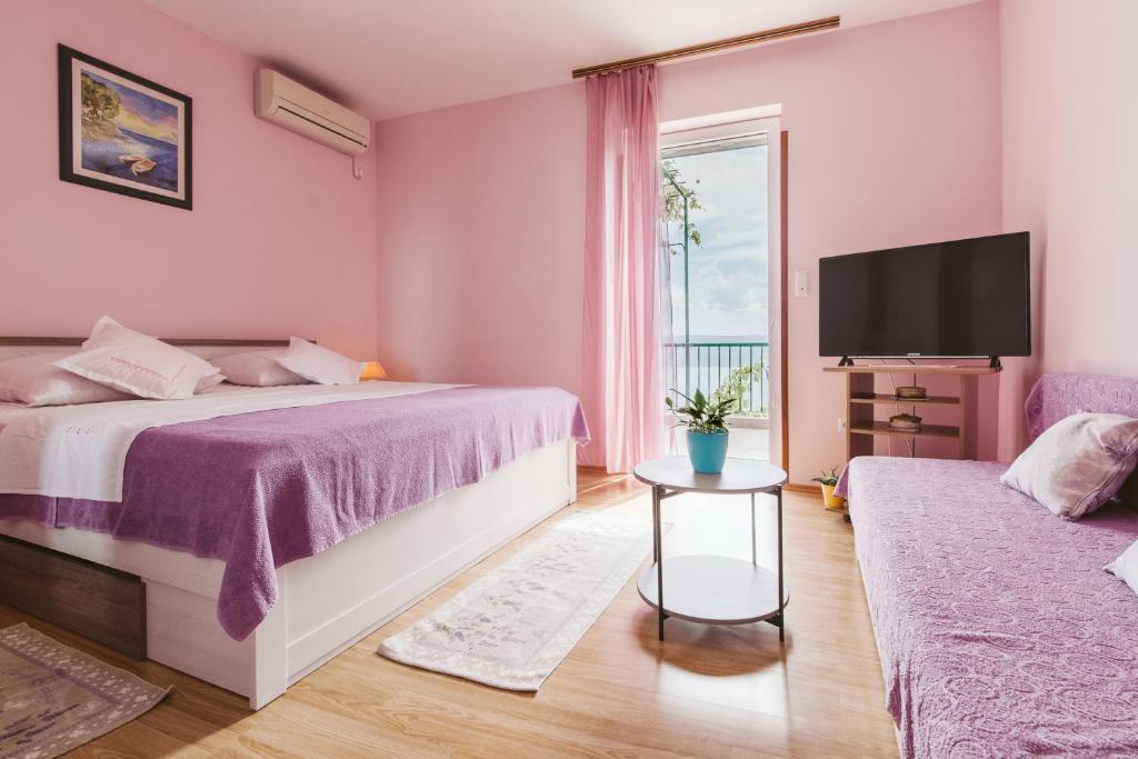 Habitación de color rosa con cama y TV en Apartment Kuzmanić, en Lokva Rogoznica