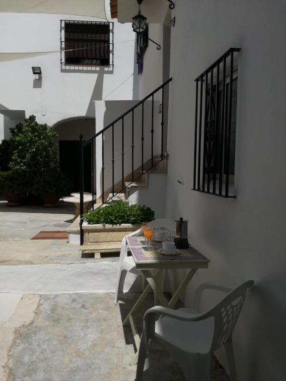 una mesa y sillas en un patio con una escalera en Casa López, en Vejer de la Frontera