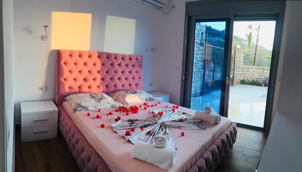 Sunset House في كساميل: غرفة نوم مع سرير وردي مع زهور حمراء عليه
