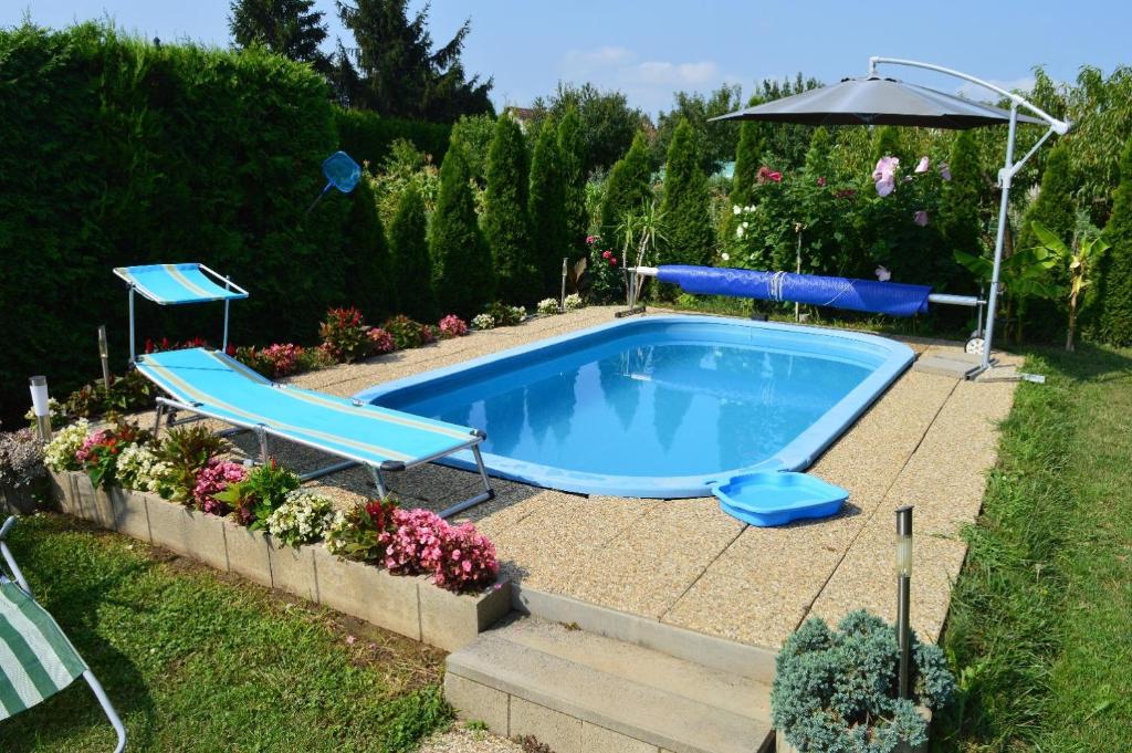 a swimming pool in a yard with an umbrella at Karolina Appartman in Balatonkeresztúr