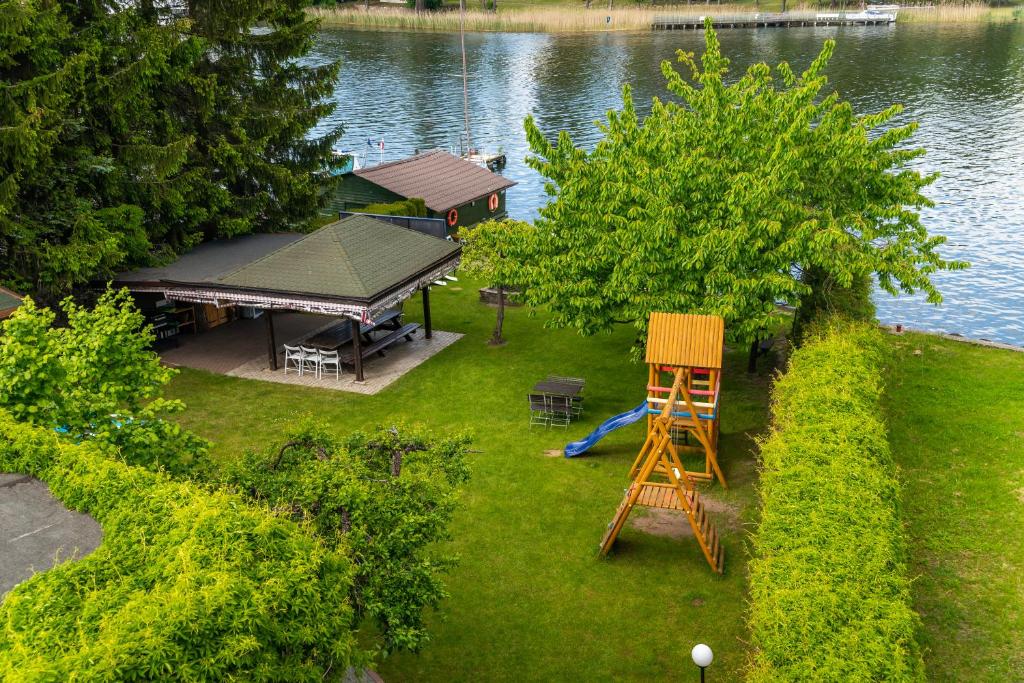 widok na trawnik z drewnianym krzesłem i placem zabaw w obiekcie Willa ATA Mikolajki w mieście Mikołajki