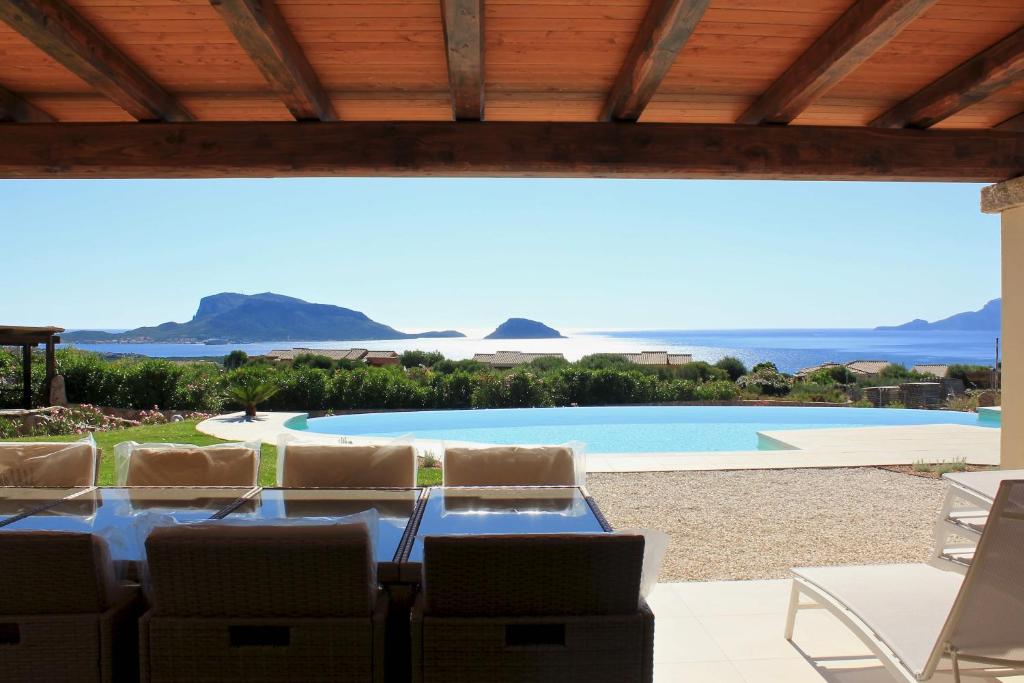 un patio avec une table et des chaises et une piscine dans l'établissement VILLA ALBA NUOVA with infinity pool & amazing sea view, à Golfo Aranci