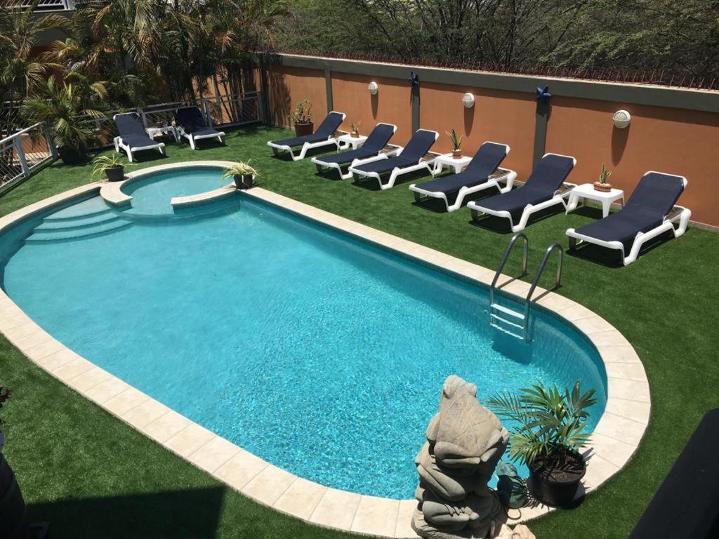 a swimming pool with chaises and chairs next to at King David Suites in Palm-Eagle Beach