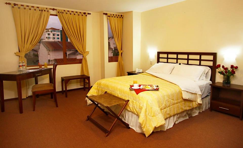 a bedroom with a bed and a table and a desk at Hotel San Sebastián Loja in Loja