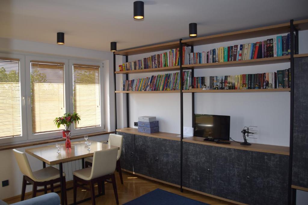 uma sala de jantar com uma mesa e uma televisão e prateleiras de livros em Apartament Kolejowa em Białystok