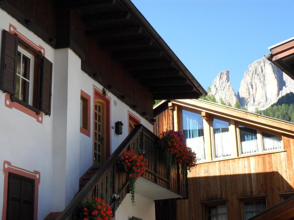 - un bâtiment avec des fleurs sur les balcons avec des montagnes en arrière-plan dans l'établissement casa claudio-APPARTAMENTI IN CENTRO, à Campitello di Fassa