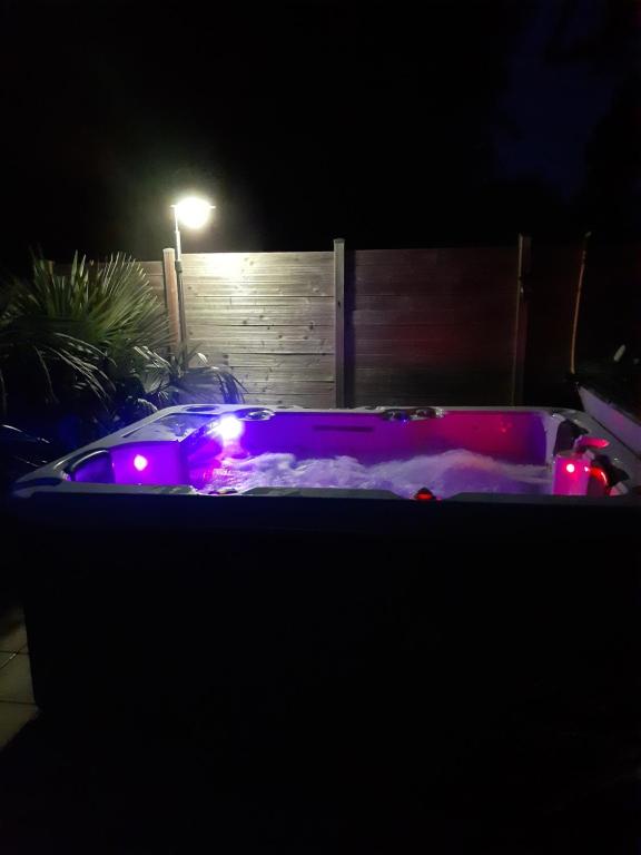 bañera de hidromasaje con luces en un patio por la noche en chambre au nuit étoile et jacuzzi prive en Pleuven