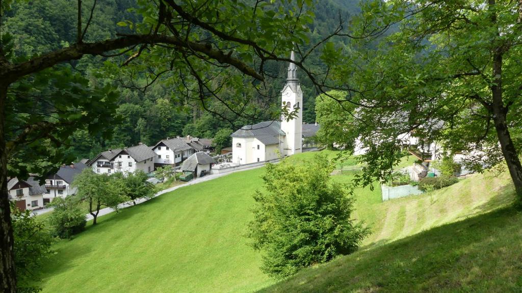 a small village with a church on a green hill at Tiha dolina in Železniki