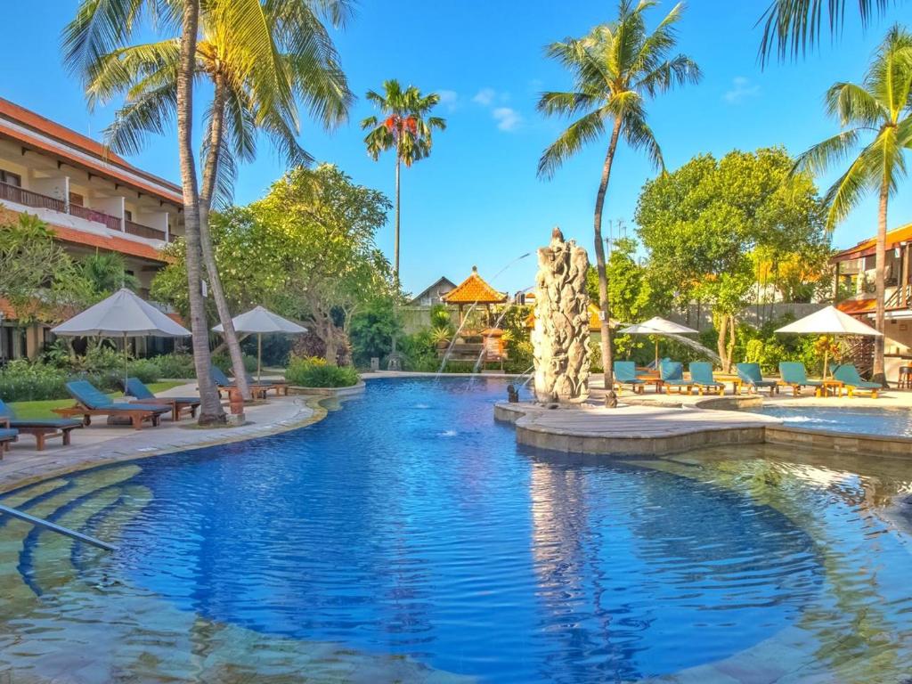 a swimming pool at a resort with palm trees at Bali Rani Hotel in Kuta