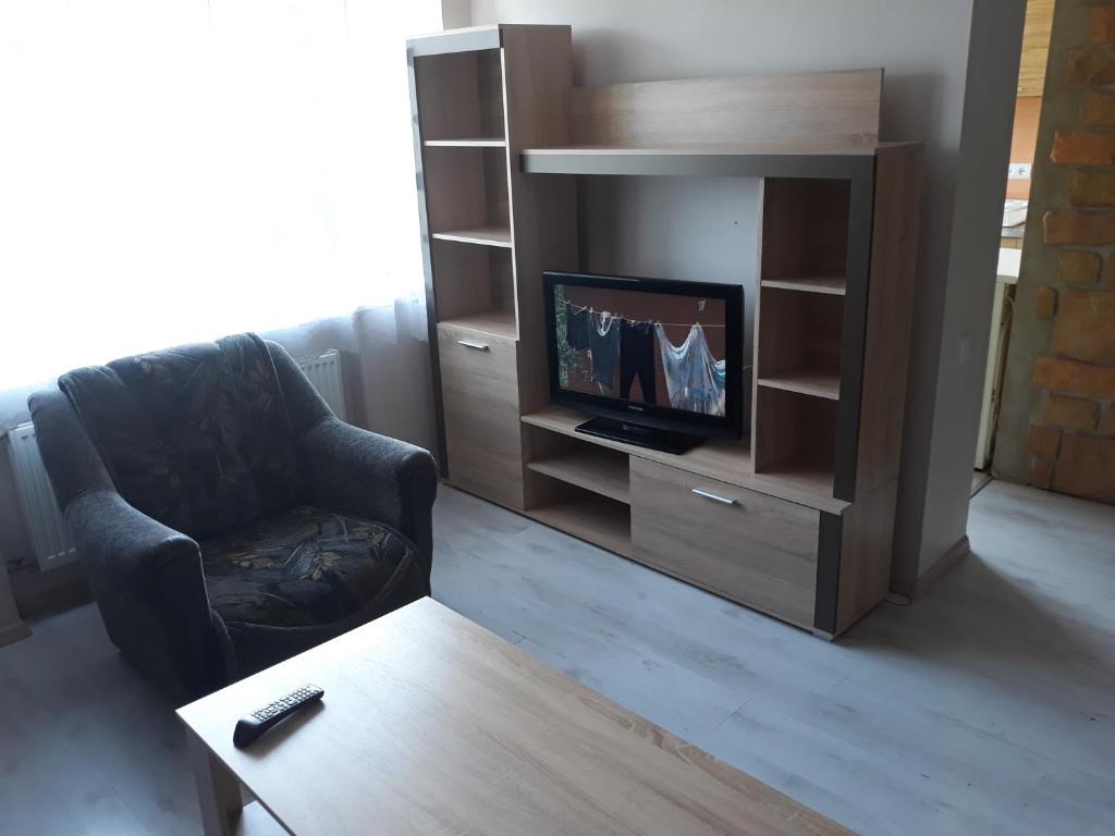 uma sala de estar com uma televisão, uma cadeira e uma mesa de centro em Brīvības 21 Apartament em Ventspils