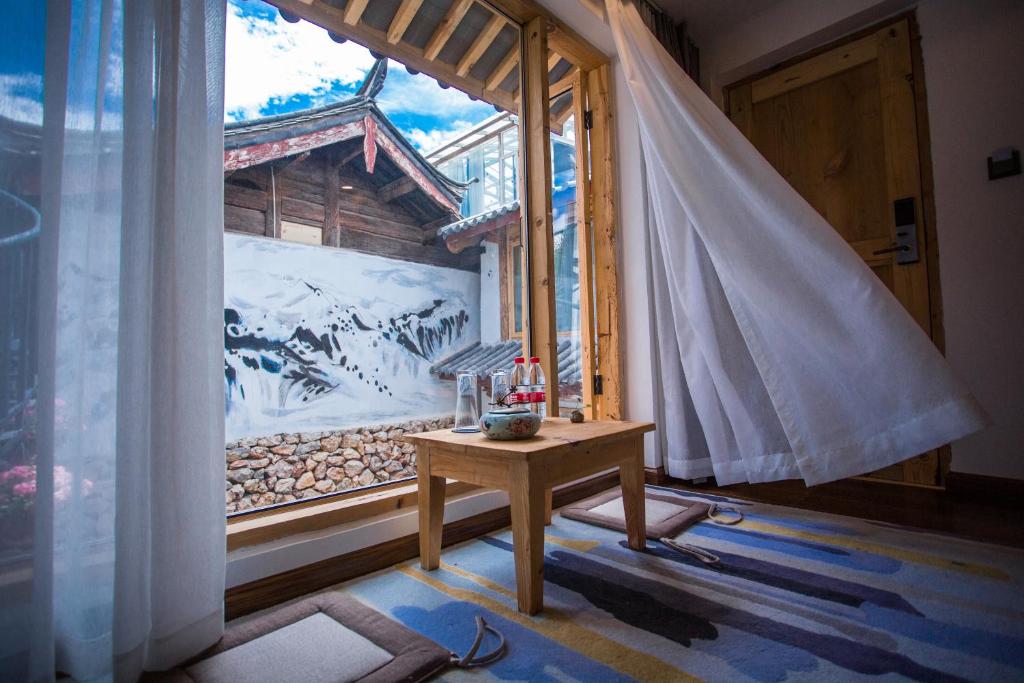 una camera con tavolo di fronte a una finestra di Lijiang Yunqi Holiday Guesthouse a Lijiang