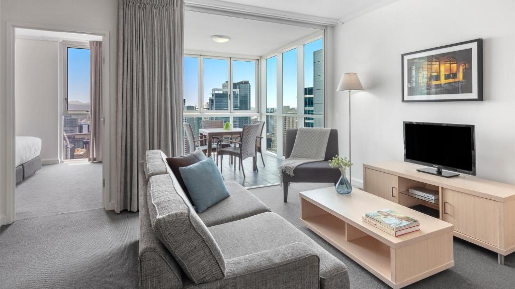 a living room with a couch and a television at Oaks Brisbane Festival Suites in Brisbane