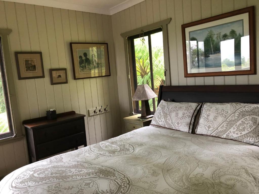 a bedroom with a bed and two windows at daintree valley cottage in Daintree