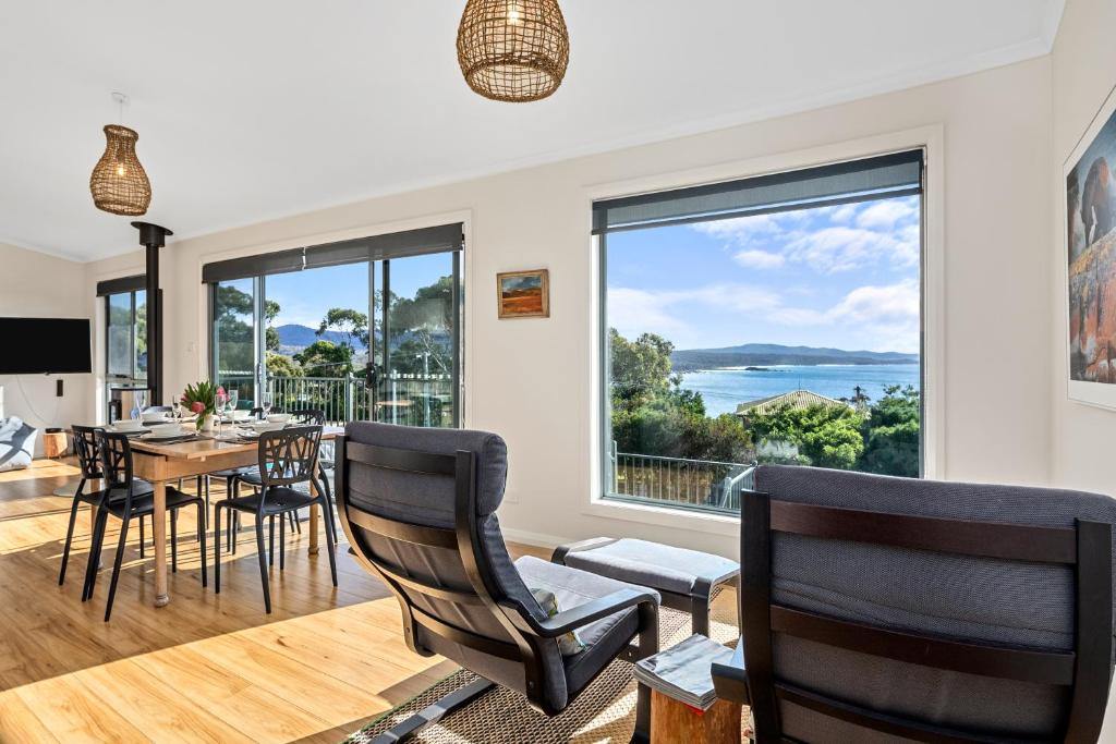 a dining room with a table and chairs and a large window at GRANITE BEACH HOUSE @ Bay of Fires in Binalong Bay