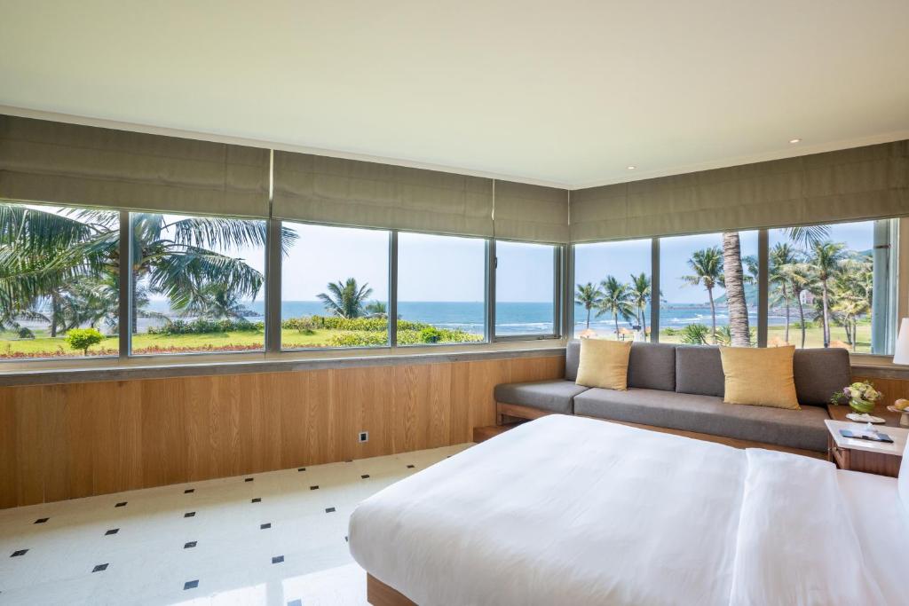 a bedroom with a bed and a couch and windows at Sunset Beach Resort in Kaohsiung