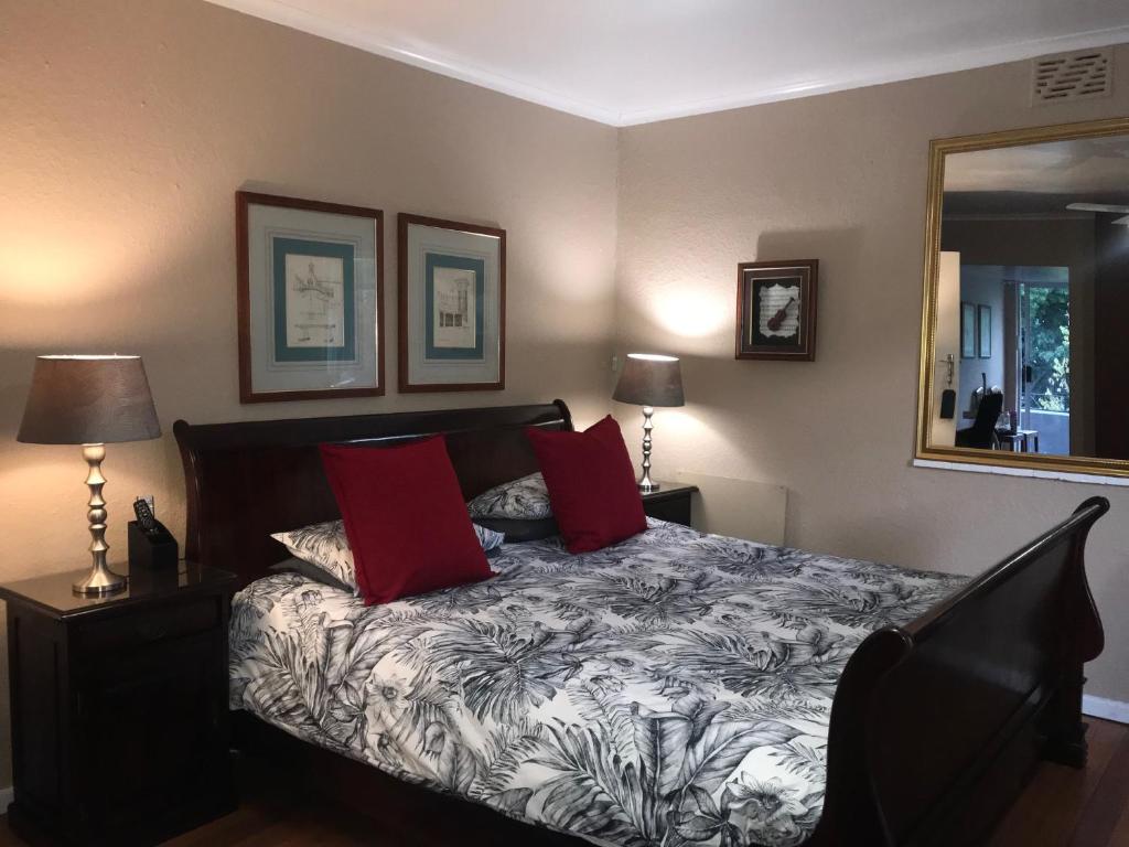 Cape Town的住宿－Authentic Newlands，一间卧室配有一张带红色枕头和镜子的床