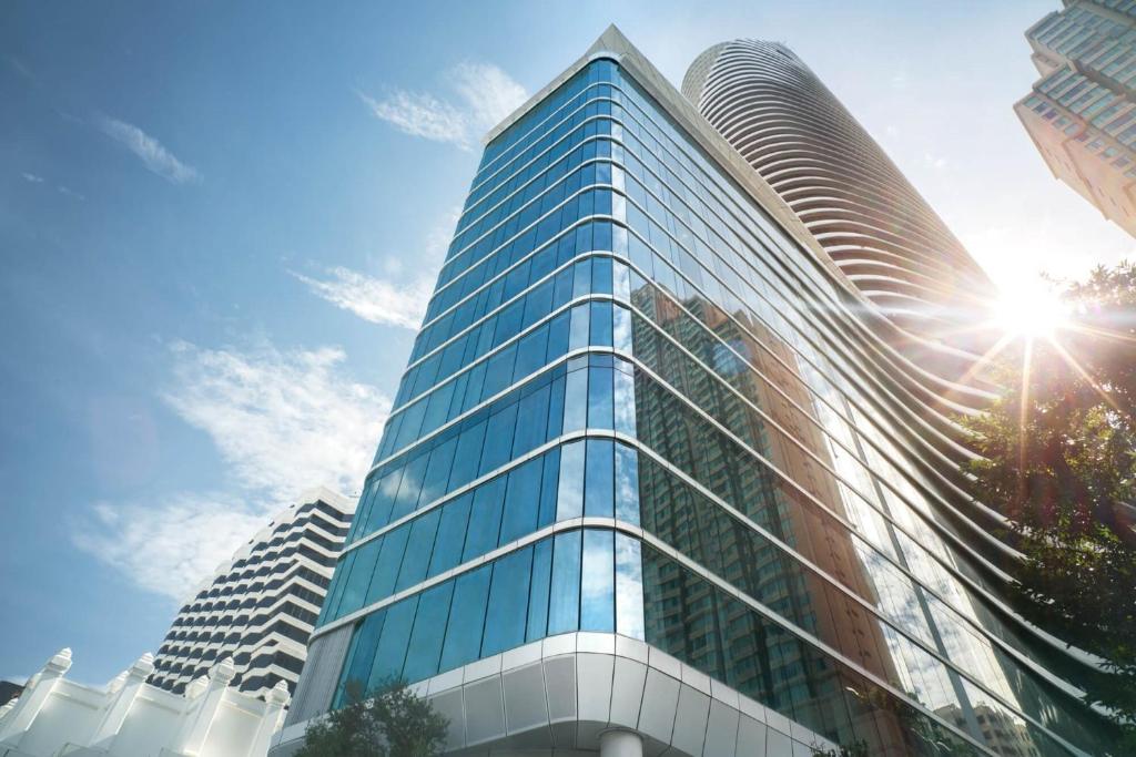 wysoki szklany budynek ze słońcem na niebie w obiekcie Magnolias Ratchadamri Boulevard Serviced Residences w mieście Bangkok