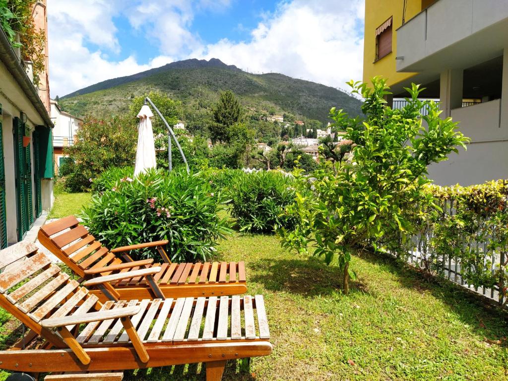 dwie drewniane ławki siedzące na dziedzińcu z górą w obiekcie MARIO Apartment with Garden w mieście Levanto