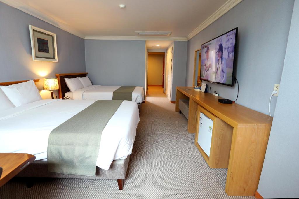 a hotel room with two beds and a flat screen tv at Prime Tourist Hotel in Busan