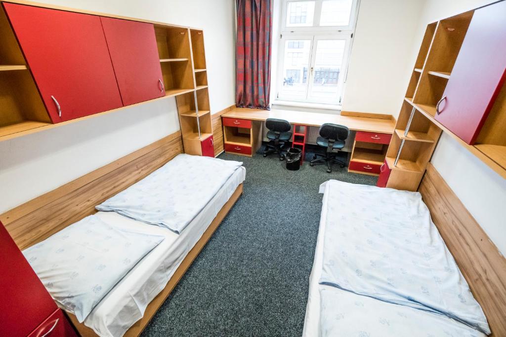 a room with two beds and a desk at Hostel Masarykova in Prague