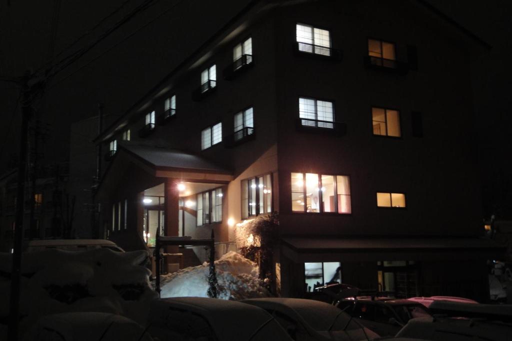 un edificio de noche con nieve delante en Hakuba Glad Inn Ebisuya, en Hakuba