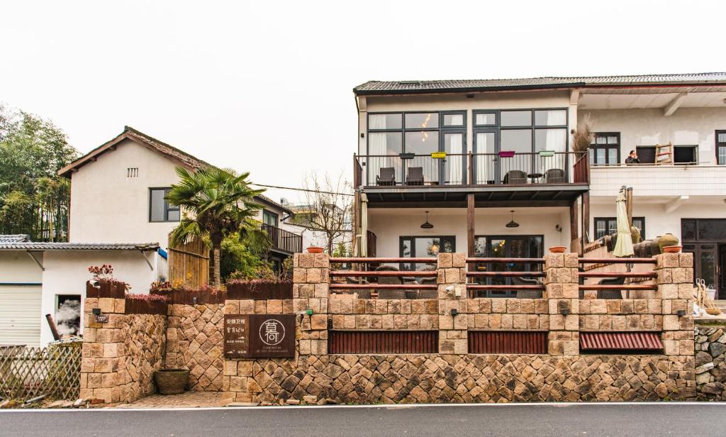 una casa con una recinzione di pietra di fronte di Mohe Hostel a Deqing