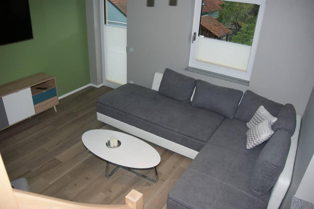 a living room with a gray couch and a table at Ferienwohnung 'Burgblick' in Wertheim