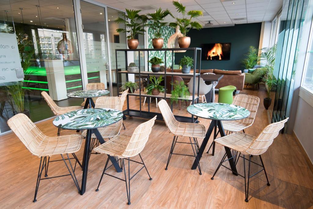 een groep tafels en stoelen in een kamer bij Court Garden Hotel - Ecodesigned in Den Haag