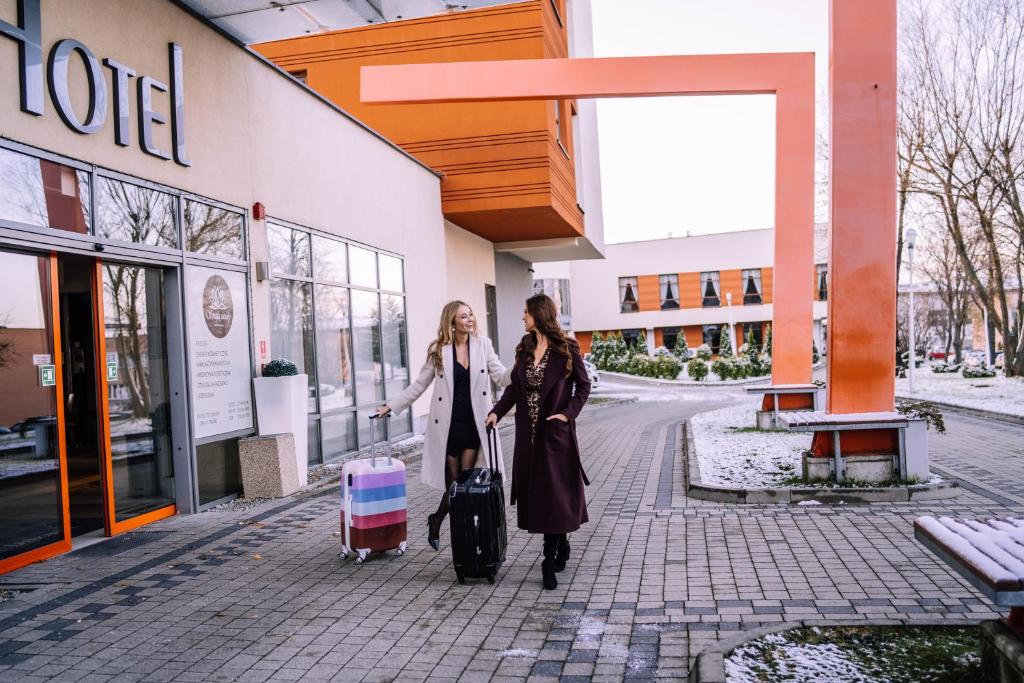 Hotel Szyndzielnia في بييلسكو بياوا: سيدتان تتمشيان على الرصيف مع أمتعتهما