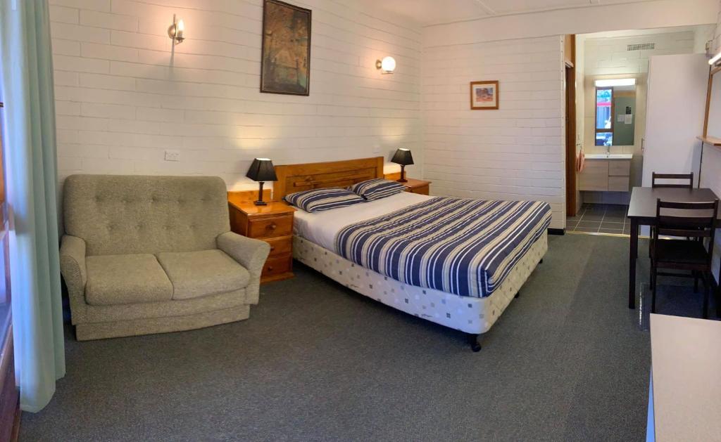 um quarto com uma cama e uma cadeira em Finley Motel em Finley