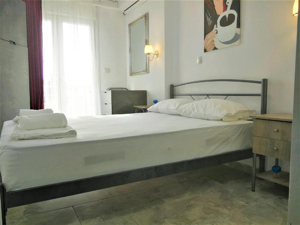 ein Bett mit weißer Bettwäsche und Kissen in einem Schlafzimmer in der Unterkunft Artistic Rent Rooms & Apartments in Nea Kallikratia