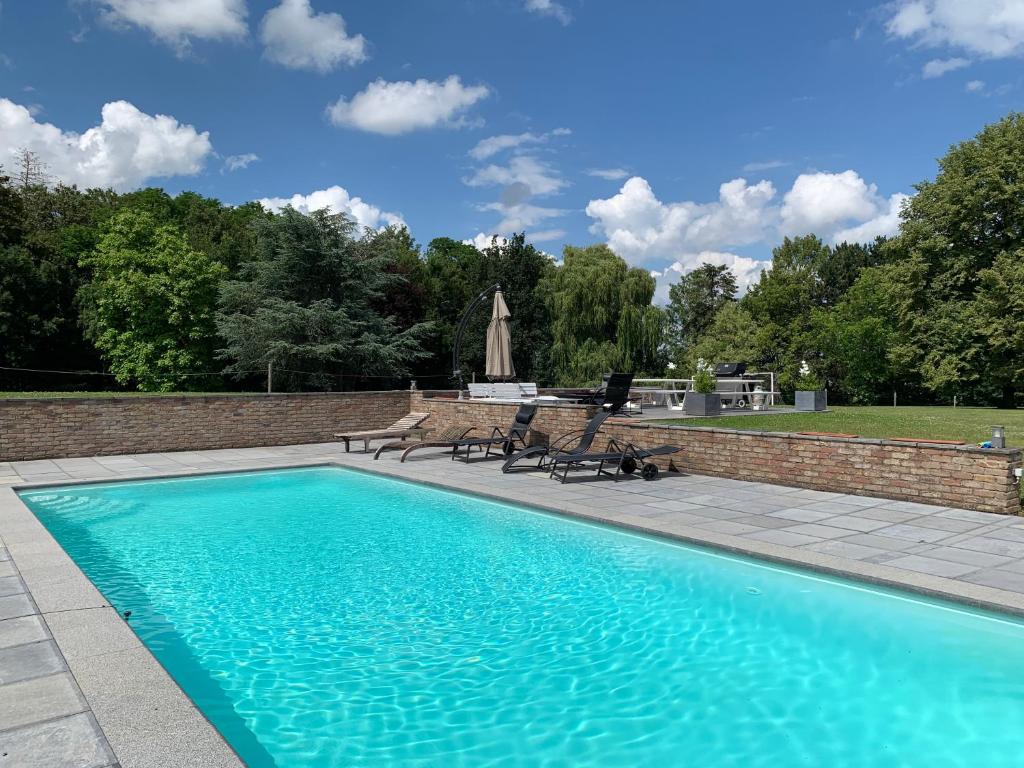 una piscina con bancos junto a una pared de ladrillo en CHAPEAUVEAU Gîte - b&b - Events, en Helecine