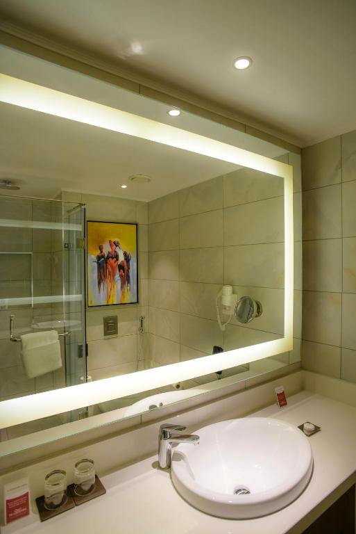a bathroom with a sink and a large mirror at Crowne Plaza Nairobi Airport by IHG in Nairobi
