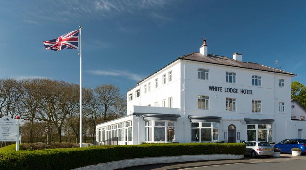ein weißes Gebäude mit einer Flagge davor in der Unterkunft The White Lodge Hotel in Filey