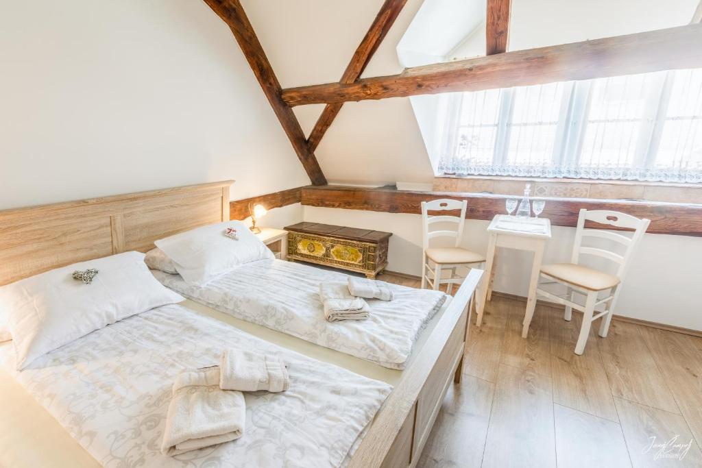 a bedroom with two beds and a table and chairs at Hiša Linhart, Hotel & Restaurant in Radovljica